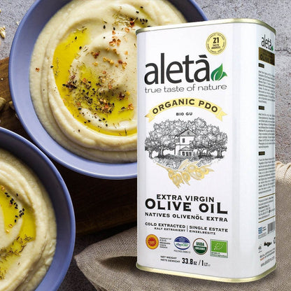 ELLORA FARMS Aleta organic PDO extra virgin olive oil tin next to bowls of creamy hummus drizzled with olive oil