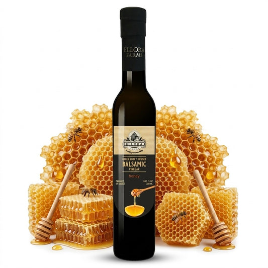 ELLORA FARMS Greek honey infused balsamic vinegar bottle displayed with honeycomb and wooden honey dippers.