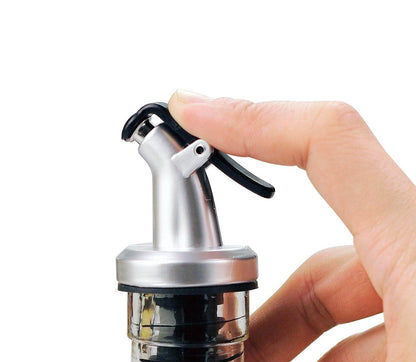 ELLORA FARMS silver chef pourer bottle spout with a black snap-on lid being operated by a hand