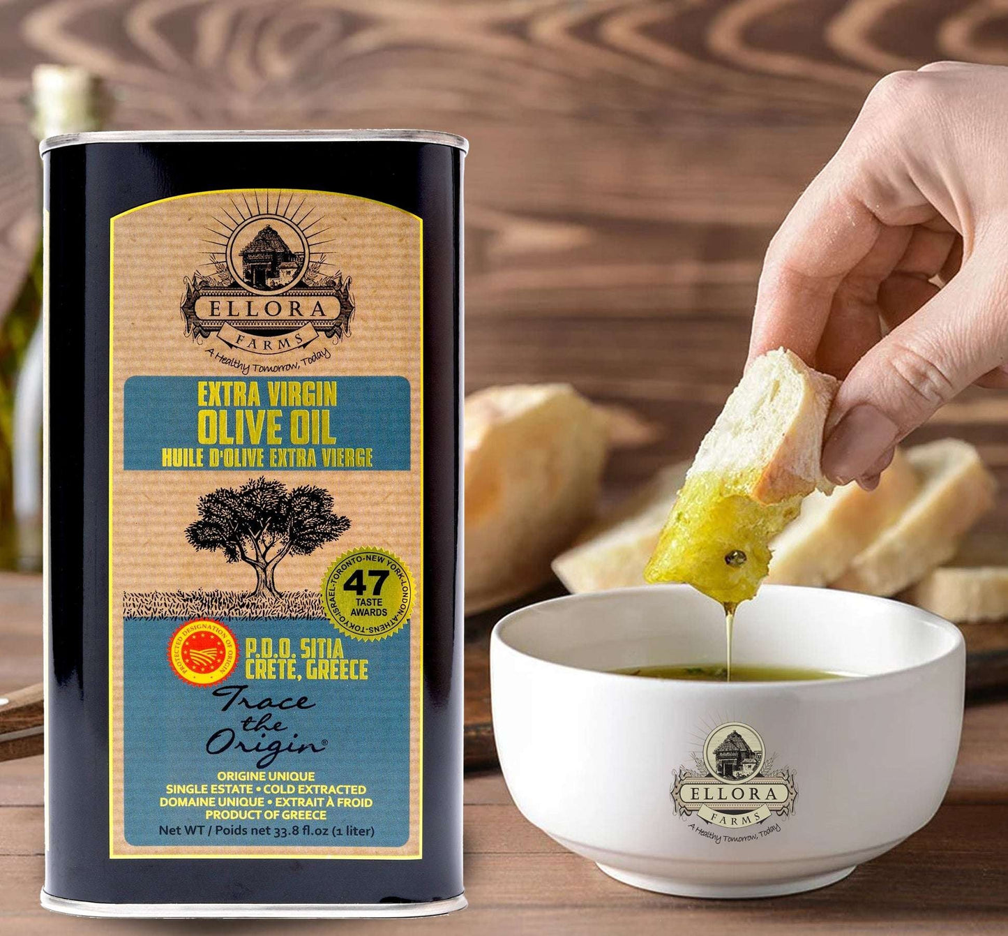 ELLORA FARMS PDO Sitia extra virgin olive oil tin with a hand dipping fresh bread into a bowl of golden olive oil.