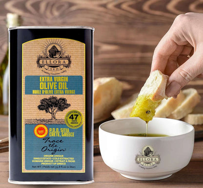 ELLORA FARMS PDO Sitia extra virgin olive oil tin with a hand dipping fresh bread into a bowl of golden olive oil.